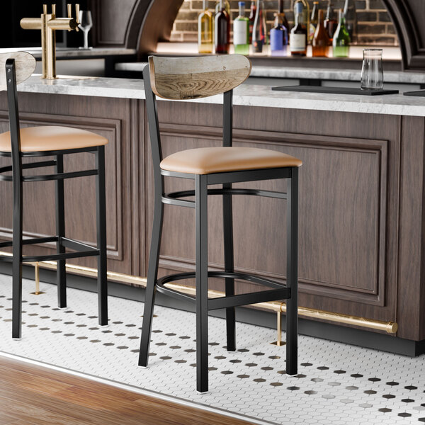 A black bar stool with a light brown vinyl seat and a driftwood-finished wooden backrest.