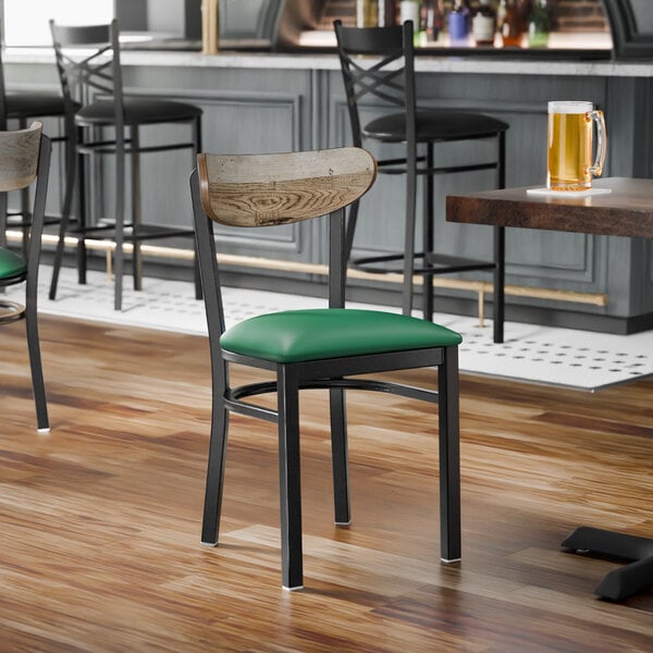 A black metal chair with a green vinyl seat and a driftwood-finished wooden backrest.