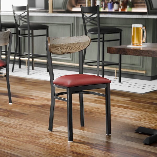A black metal chair with a burgundy vinyl seat and a driftwood-finished wooden backrest.