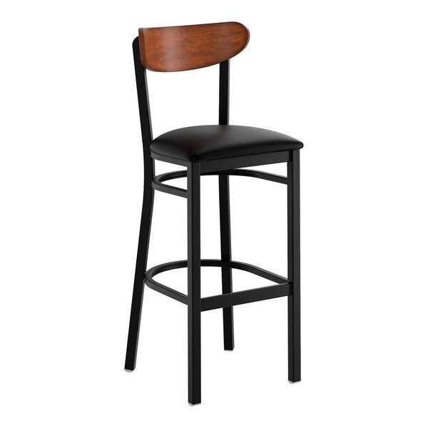 A black metal bar stool with a black vinyl seat and an antique walnut wood backrest.