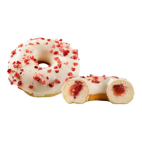A donut topped with white icing and red berry pieces, filled with a berry and cream filling.