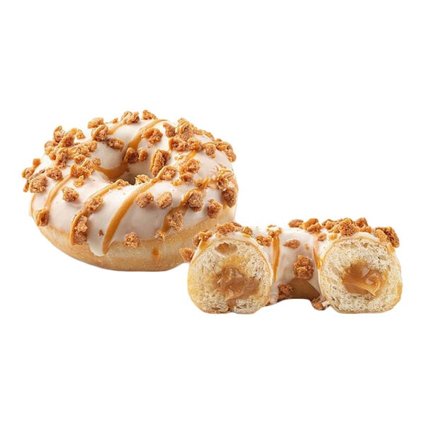 A donut filled with cookie butter, topped with white icing and cookie crumbs, shown whole and cut in half.
