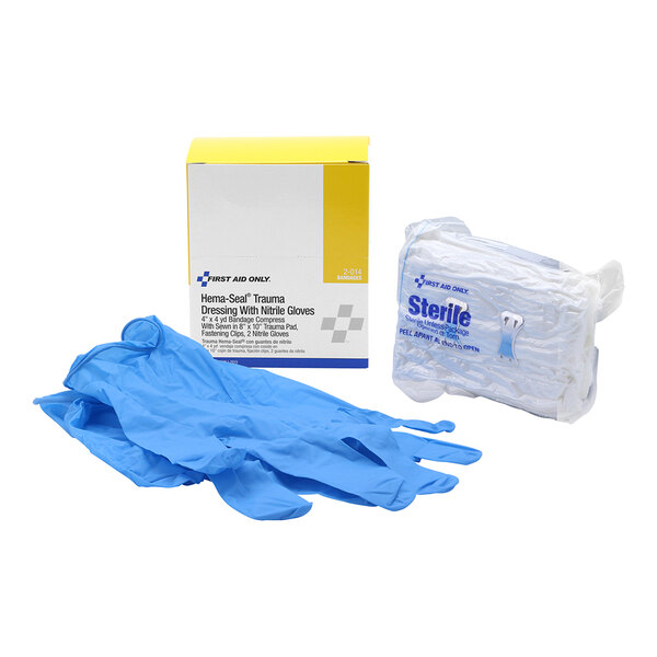 A trauma dressing kit with blue nitrile gloves and a sterile dressing pad.