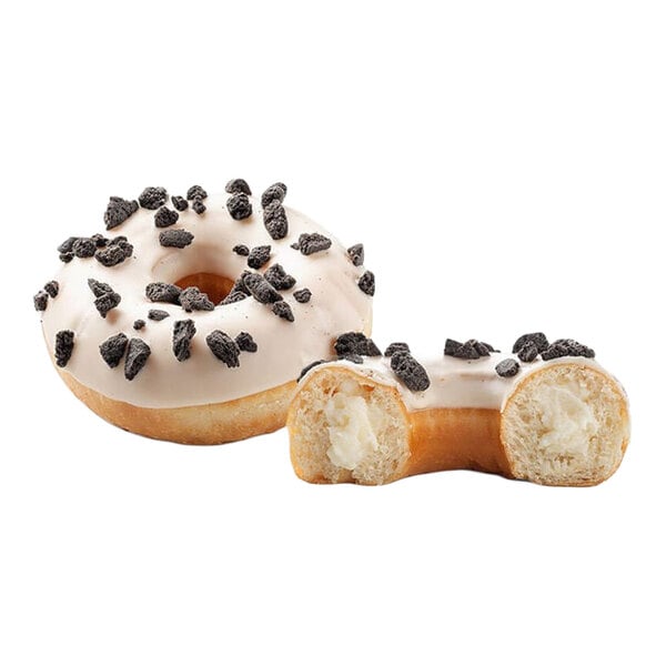 A cookies and cream filled donut topped with white icing and chocolate cookie pieces, shown whole and cut in half to display the cream filling.