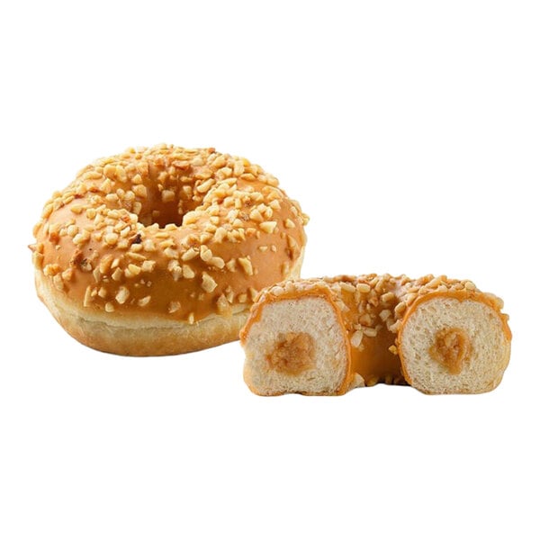 A caramel-filled donut topped with caramel glaze and chopped nuts, shown whole and cut in half.
