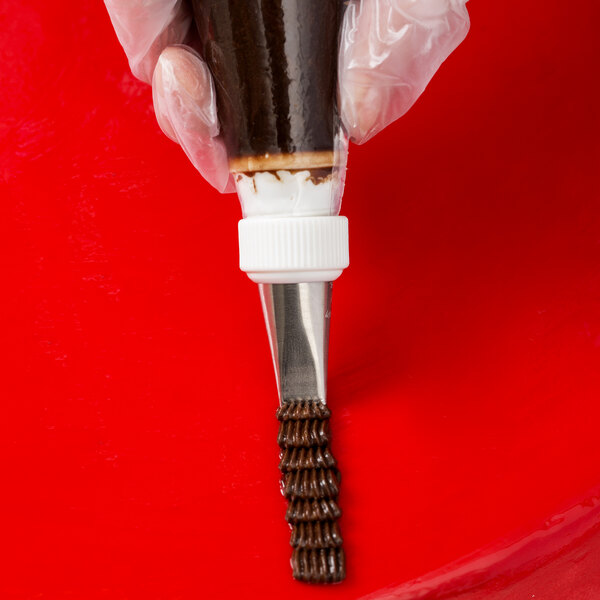 A metal basketweave piping tip attached to a piping bag being used to pipe chocolate icing.