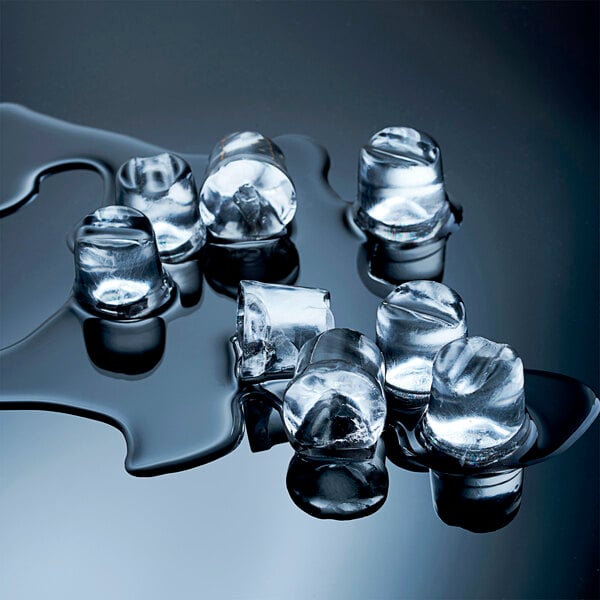 A group of clear, cylindrical ice cubes partially melted on a reflective surface.