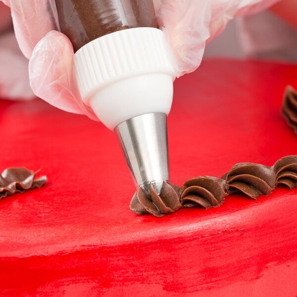 A closed star piping tip being used to decorate a cake with chocolate icing.