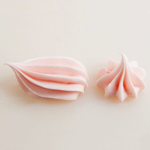 A set of two pink frosting decorations created using a closed star piping tip.