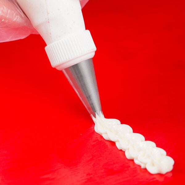 An open star piping tip being used to pipe icing onto a surface.