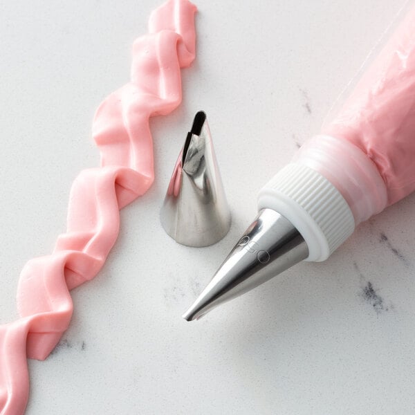A metal ruffle piping tip and a piping bag filled with pink icing, used for cake decorating.