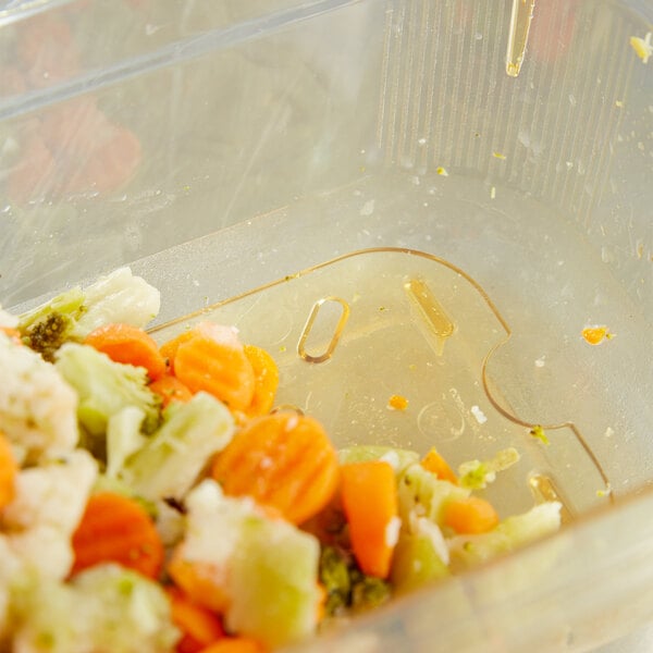 A Vollrath plastic food pan with a carrot and vegetables in it.