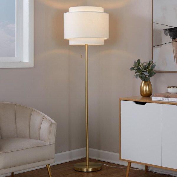 A gold floor lamp with an off-white tiered linen shade.