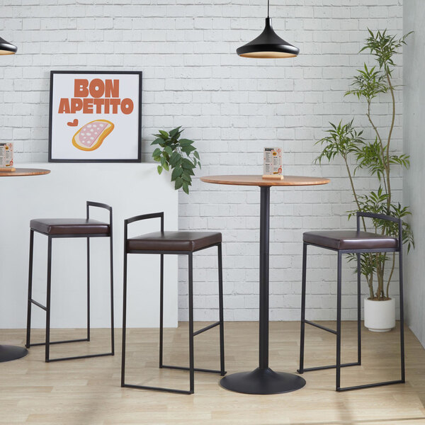 A pair of black metal barstools with low backs and brown faux leather seats.
