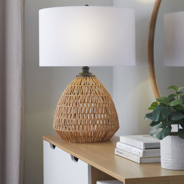 A table lamp with a natural rattan base and a white linen drum shade.