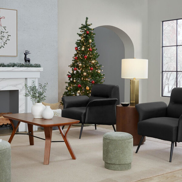 A modern table lamp with an antique brass base and a white linen drum shade placed on a side table in a living room setting.