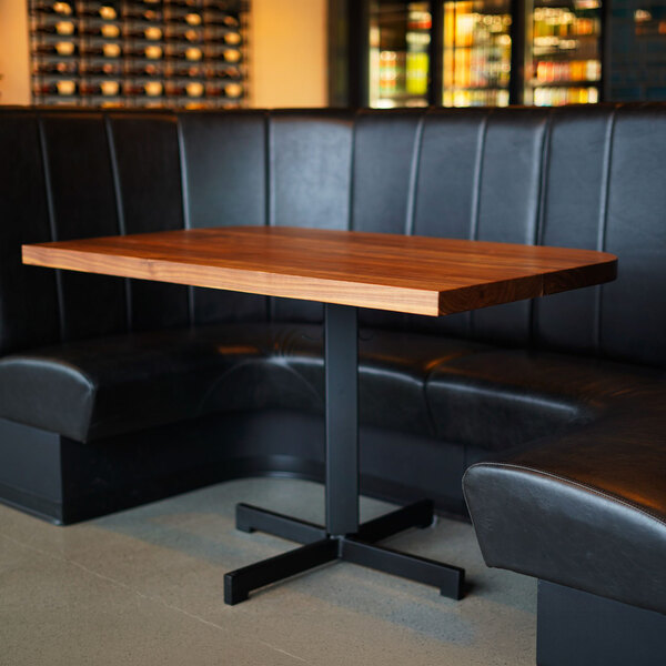 A large black half-circle booth with vertical channel upholstery and a high back, positioned around a wooden table.