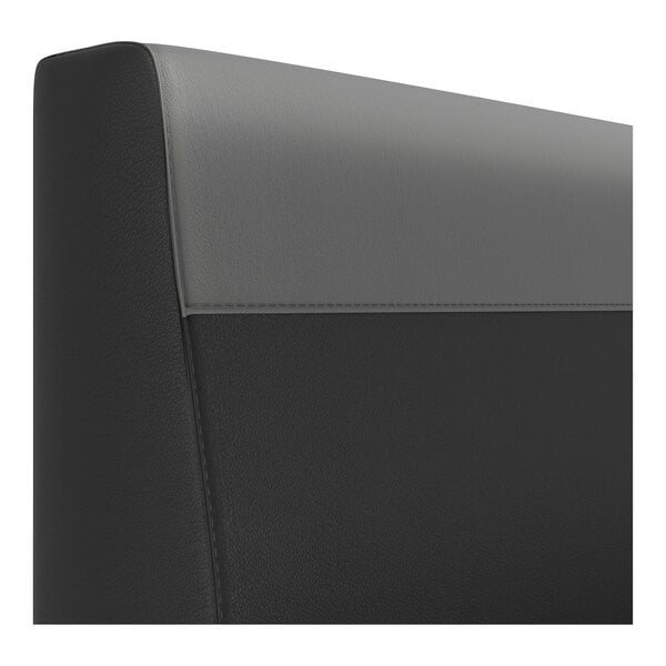 A close-up view of a two-tone upholstered booth backrest with a graphite head roll and a black lower section.