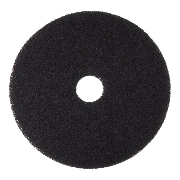 A black circular floor stripping pad with a hole in the center.