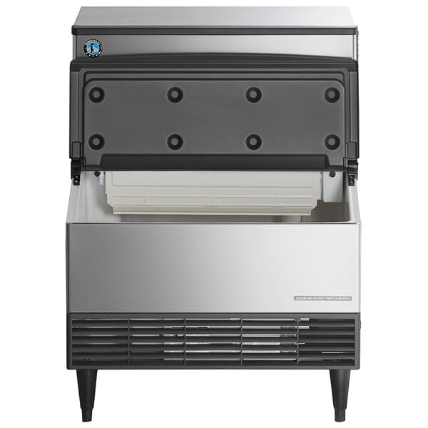A stainless steel undercounter ice machine with an open bin and a black front panel.