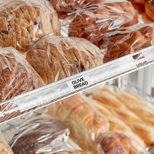 A clear clip-on label holder attached to wire basket shelving, displaying a label for olive bread.
