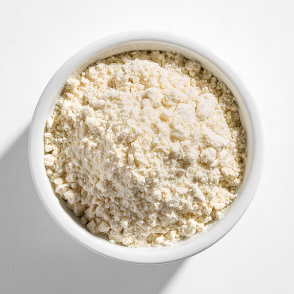 A white bowl filled with a light-colored, crumbly powdery mix, viewed from above.