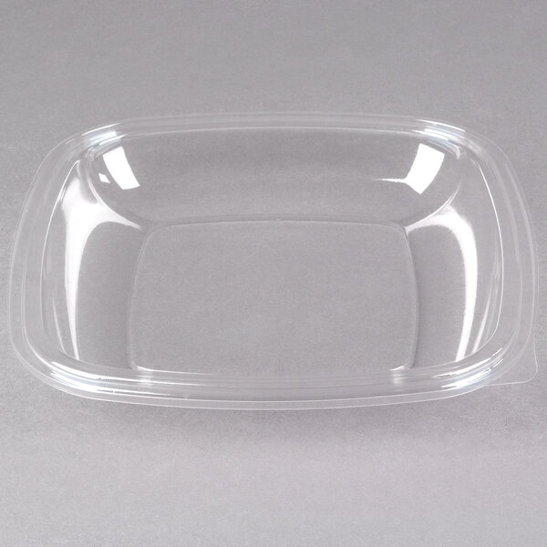 A clear plastic Sabert bowl with a clear dome lid on a white surface.