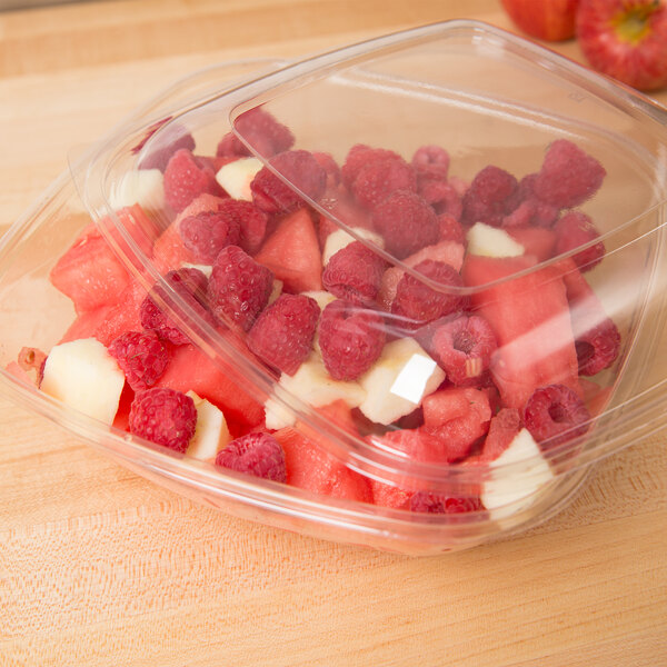 A plastic container of fruit with a clear dome lid.
