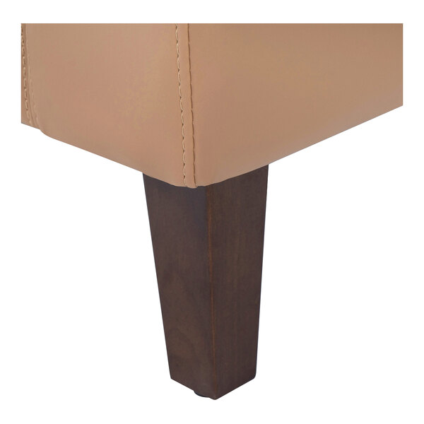 A close-up of a wooden leg on a cognac-colored LeatherSoft loveseat.