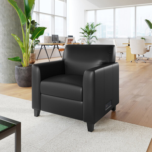 A black leather armchair with wooden feet and a built-in charging bank, placed in a modern office setting.