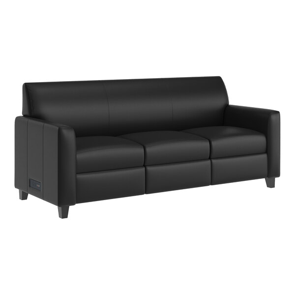 A black leather sofa with three seats, wooden feet, and built-in charging banks on the side.