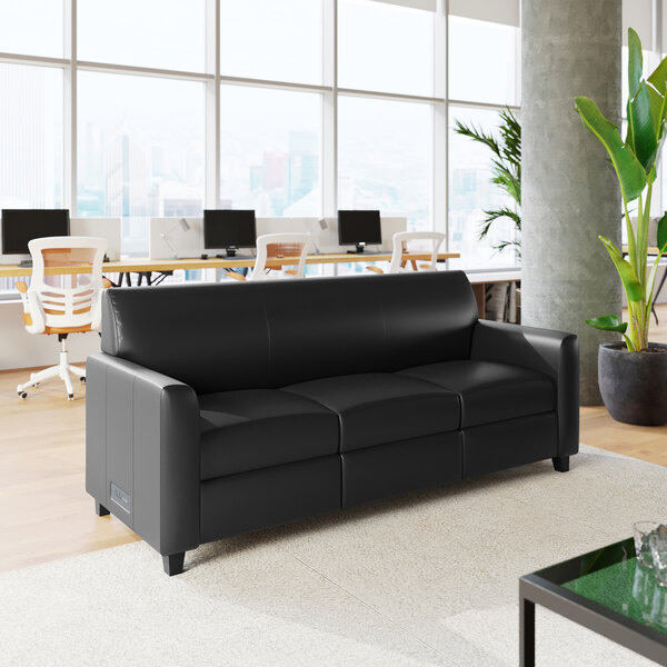 A black leather sofa with three seats, wooden feet, and built-in charging banks.