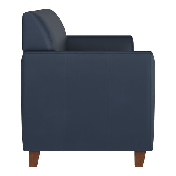 A navy blue leather sofa with wooden feet and a boxy, modern design.