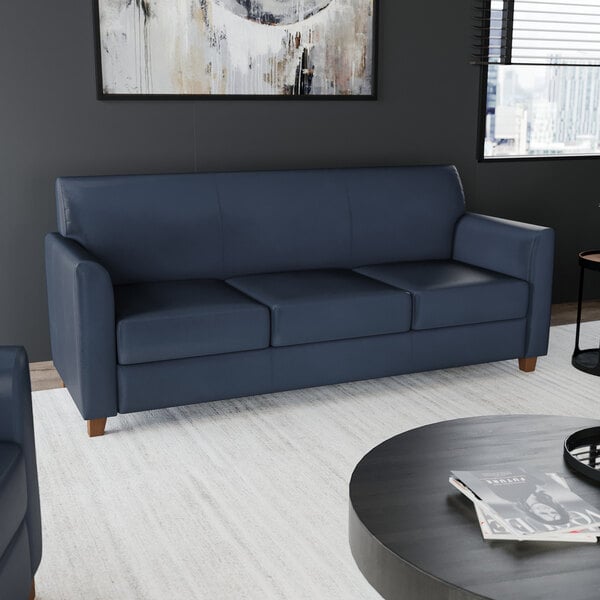 A navy blue three-seat sofa with wooden feet and a modern design.