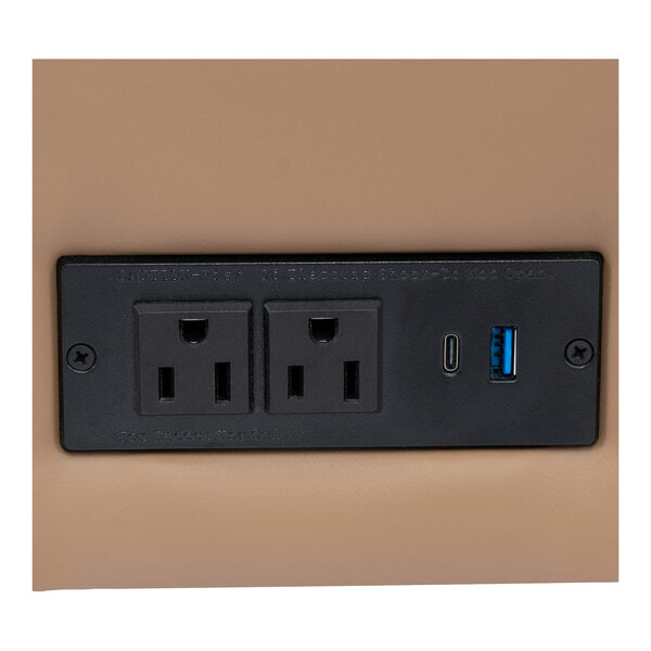A built-in charging bank with two power outlets, one USB-C port, and one USB-A port on a cognac-colored chair.