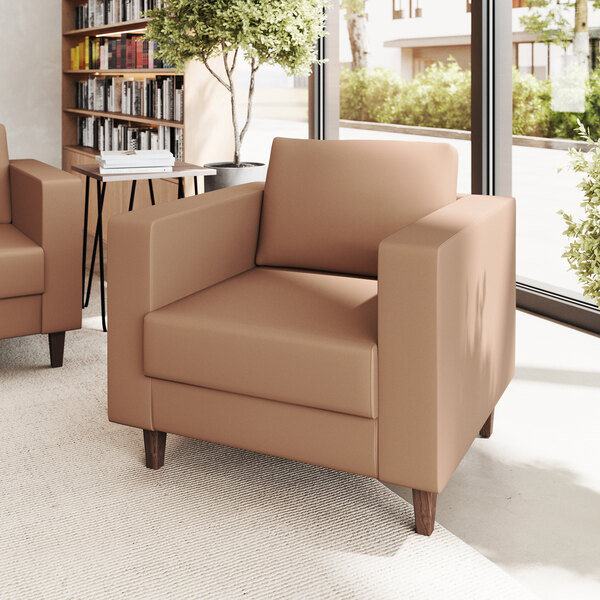 A modern cognac-colored leather chair with wooden feet and built-in charging bank.