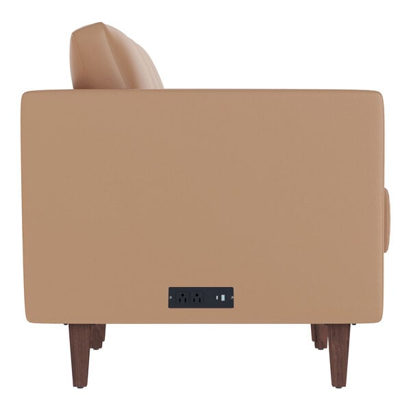 A cognac-colored leather sofa with wooden feet and two built-in charging banks on the side.