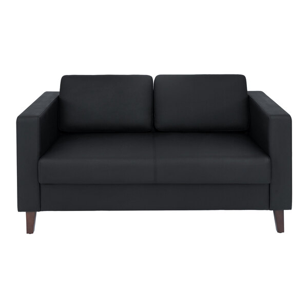 A black leather loveseat with wooden feet and a charging bank.