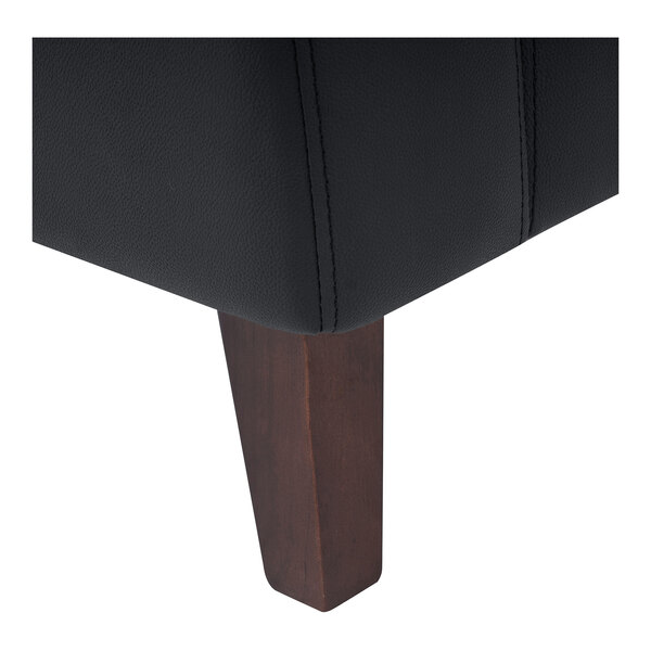 A close-up of the wooden leg and black LeatherSoft upholstery of a loveseat.
