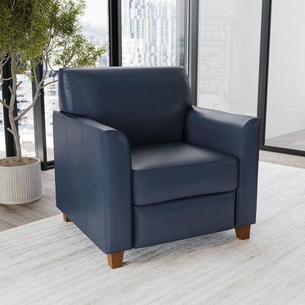 A navy blue leather armchair with wooden feet.