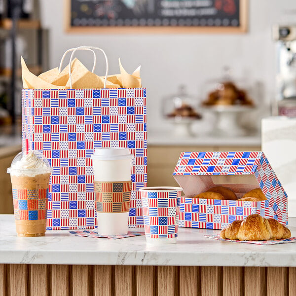 A paper shopping bag with handles featuring a red, white, and blue patriotic USA print design.