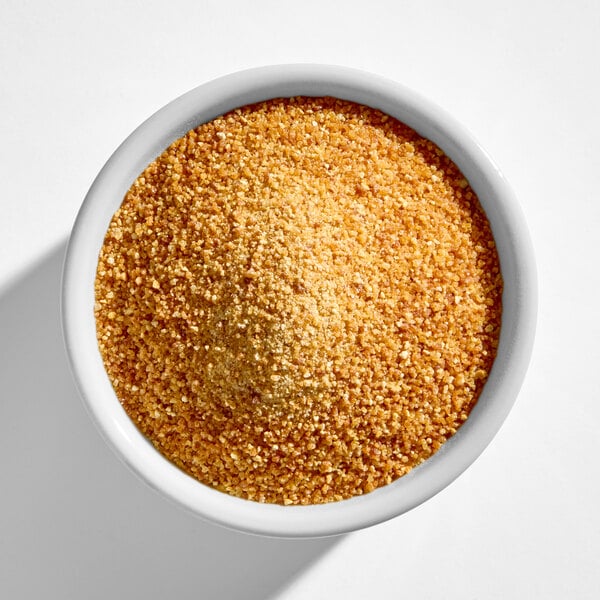 A white bowl filled with golden brown unseasoned gluten-free bread crumbs.