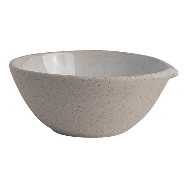 A round white stoneware spouted bowl with a speckled finish.