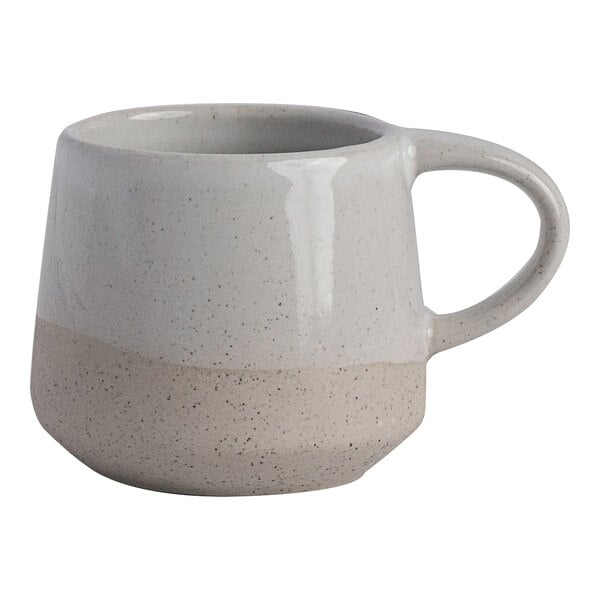A small white stoneware espresso cup with a speckled two-tone design and a handle.