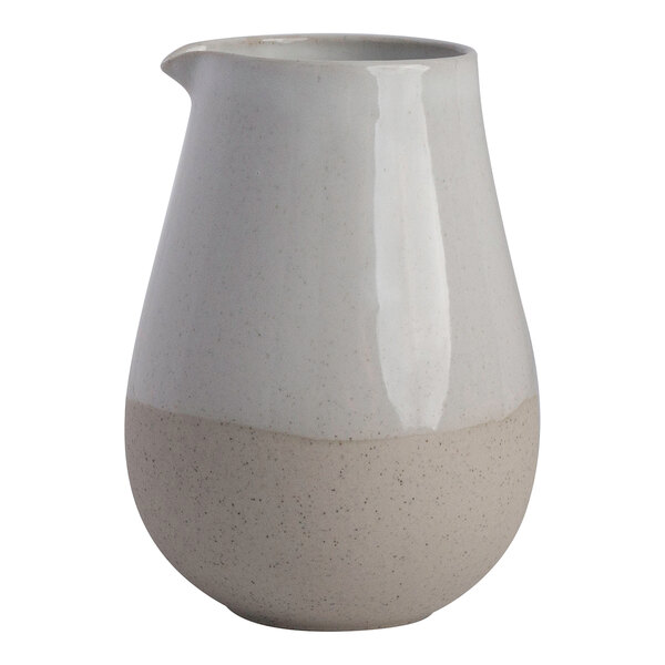 A two-tone white and beige stoneware creamer with a rounded body and a small spout.