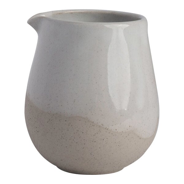 A small white stoneware creamer with a rounded shape and a spout.
