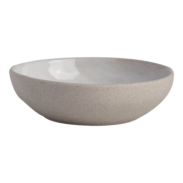 A round white stoneware bowl with a speckled exterior and a smooth interior.
