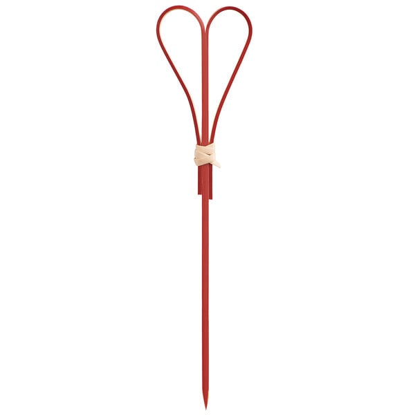 A red bamboo food pick or skewer with a heart-shaped top and a small beige wrap at the base of the heart.