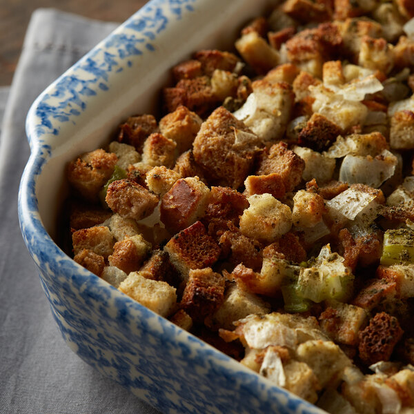 A casserole dish filled with bread stuffing containing chunks of bread, onions, and celery.