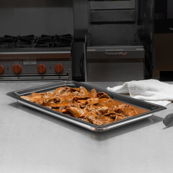 A Vollrath Stainless Steel Steam Table Pan with food on a counter.